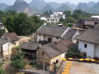 Rooftop view of Chinese farmhouses, moutains in the background.