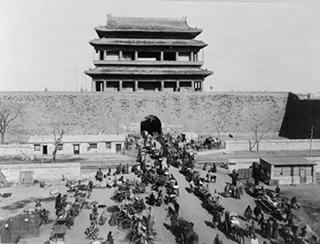 A black and white photo of a busy street scene in front of Hata-men gate, Beijing, China.