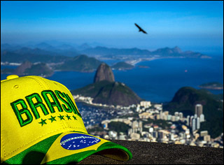 A photograph with a cap that says "Brasil" in the foreground, with the view of the city and ocean in the background.