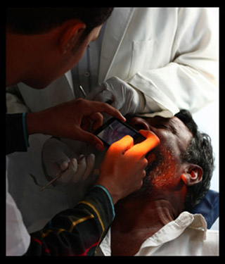 Photo of a health care worker taking a photo of the inside of a patient's mouth using a cell phone.