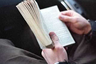 Focus on a man's hands holding a small book open.