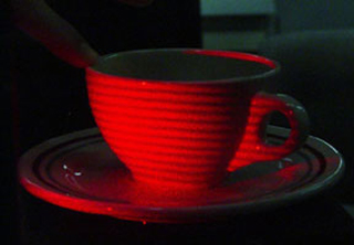 Light from a laser-illuminated coffee cup interferes with a holographic image of itself in the laboratory, producing a series of coarse interference fringes.