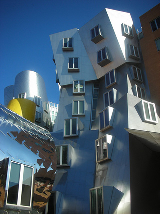 A building made of silver stainless steel, with walls that slope in angles and curves.